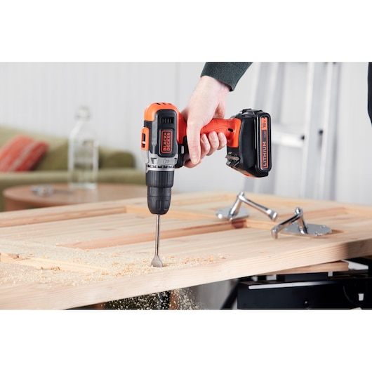 BLACKDECKER cordless drill BCD003C1 in use drilling wood, side angle, orange and black tool.