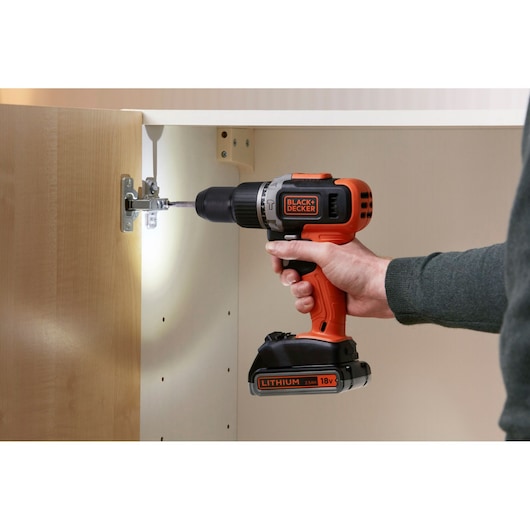 BLACK+DECKER BCD003MEM2K cordless drill being used to install a hinge on a cabinet.