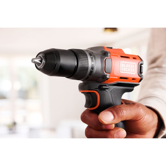 A BLACK+DECKER cordless drill held in a hand, shown close up indoors.