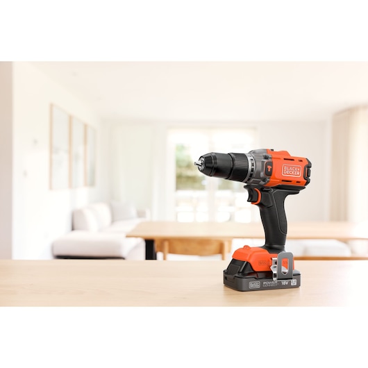 BLACK+DECKER cordless drill on a wooden table in a bright modern living room.