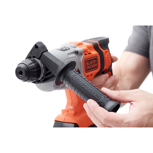 Close-up photo of BLACK+DECKER BCD900E2K cordless drill in use, showing black side handle and orange body.