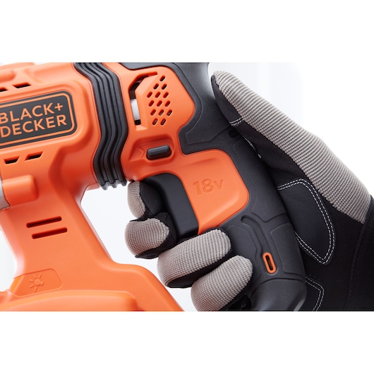 Close up photo of BLACK+DECKER BCD900E2K cordless drill handle, orange and black, with gloved hand holding it.