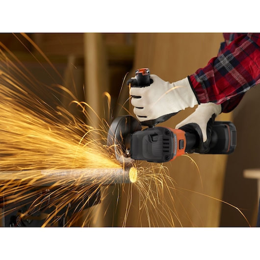 Photo of BLACKDECKER BCG6L8N cordless angle grinder cutting metal pipe with sparks flying, operator wearing gloves