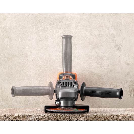 BLACKDECKER BCG720N angle grinder with three handles, front view on concrete background.