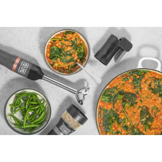 BLACK+DECKER BCKM1016KSG hand blender with attachments, surrounded by bowls of curry, green chilies, and spices, top view.