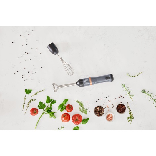 Photo of BLACKDECKER hand blender BCKM1012KG with whisk attachment, surrounded by fresh herbs, tomatoes, and spices.