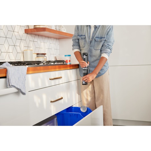 Photo of BLACKDECKER BCKM1016KSB handheld can crusher used in a kitchen near a blue recycling bin.