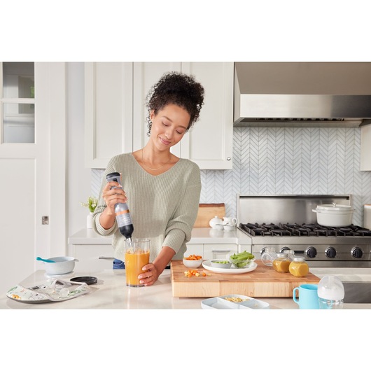 BLACKDECKER BCKM1016KSG hand blender blending orange juice in a glass on a kitchen counter.