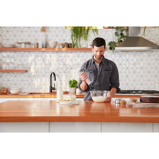 Photo of BLACKDECKER BCKM1016KSG hand mixer being used to mix batter in a glass bowl on a modern kitchen counter.