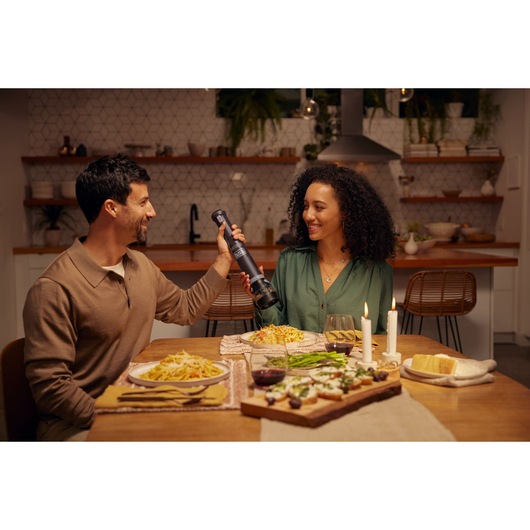 BLACKDECKER BCKM101SPFF electric grinder used at dinner table with pasta dishes and candles.