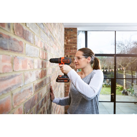BLACKDECKER BCKSB04 cordless drill in use on brick wall indoors.