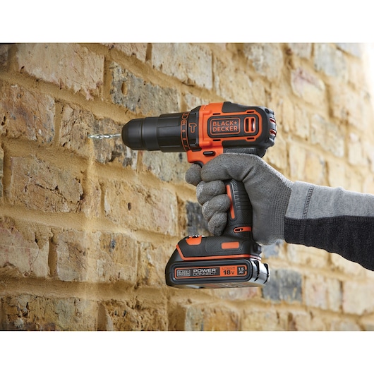Photo of BLACK+DECKER BCKSB04 cordless drill being used on a brick wall, user wearing work gloves.