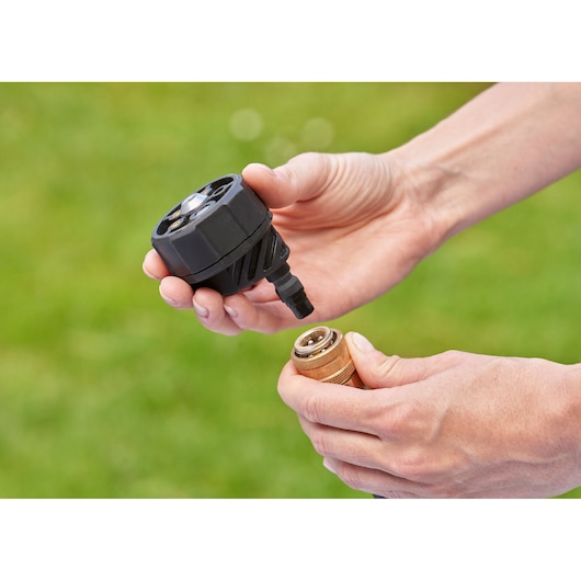 BLACKDECKER BCPC18B connector attachment and brass fitting held in hands outdoors.