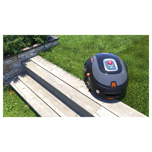 BLACKDECKER BCRMW121 robotic lawn mower on grass beside wooden steps, outdoor photography.