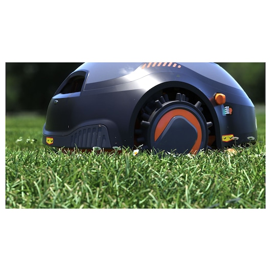 BLACKDECKER BCRMW122 robotic lawn mower side view on grass, dark grey with orange wheel details.