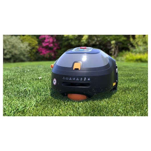 Photo of BLACKDECKER BCRMW123 robotic lawn mower on grass, showing front angle with visible control panel and safety icons.
