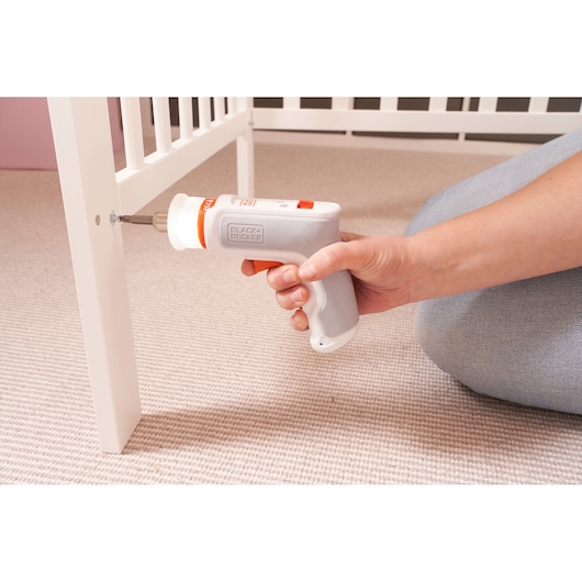 Photo of BLACKDECKER BCRTA01 cordless screwdriver in use assembling a white crib on carpet.