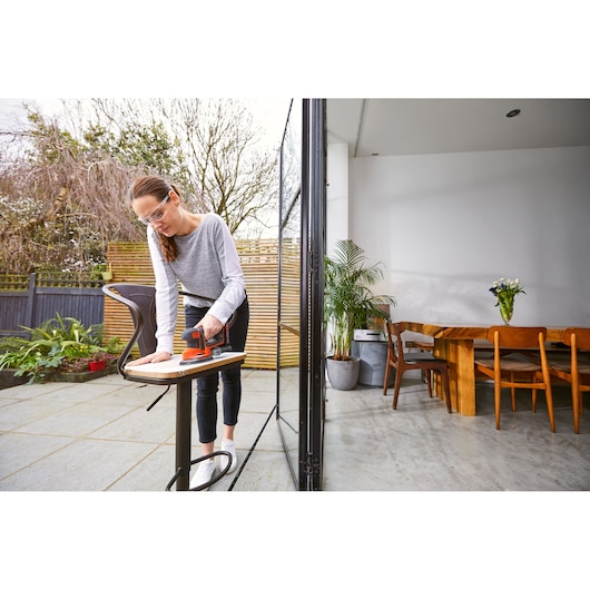 BLACKDECKER BDCDS18 cordless sander in use outdoors on a wooden surface.