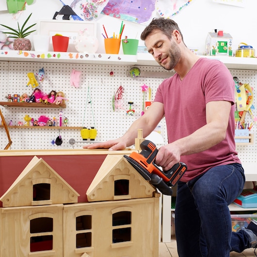 BLACKDECKER BDCDS18 cordless sander used on wooden dollhouse in craft room.
