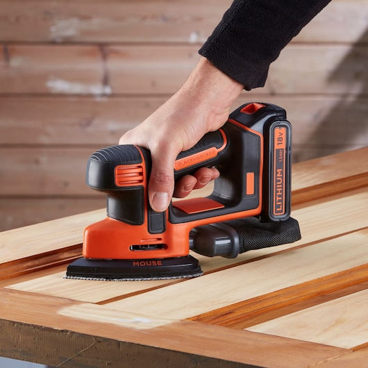 BLACKDECKER BDCDS18 cordless mouse sander with lithium battery sanding wooden surface, close-up.
