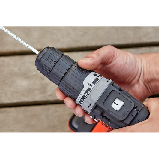 Close-up of BLACKDECKER BDCHD12S1 cordless drill held in hand, showing adjustment ring and drill bit.