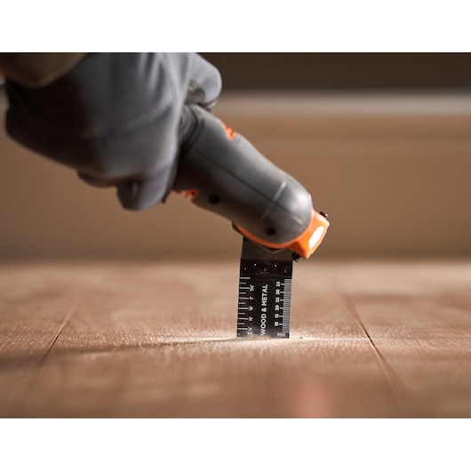 BLACKDECKER BDCOS18D1K oscillating tool used on wooden floor, close-up view.