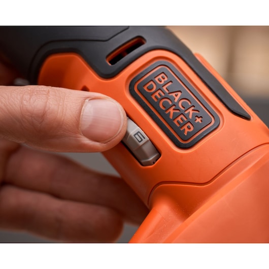 Close-up photo of BLACK+DECKER BDCOS18N orange power tool with hand adjusting speed switch.