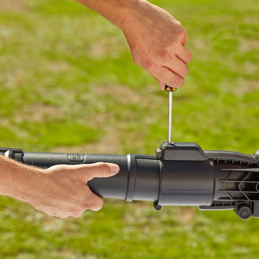 Photo of BLACKDECKER BEBLV260 leaf blower being assembled outdoors with a screwdriver.