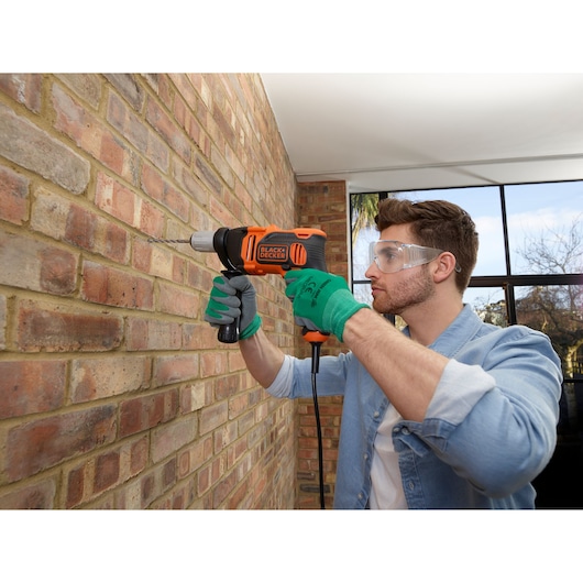 BLACKDECKER BEH850K corded hammer drill used on brick wall, photography of power tool in action.