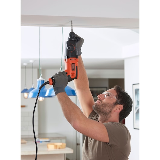 Photography of BLACKDECKER BEHS01K corded hammer drill in use for overhead drilling indoors.