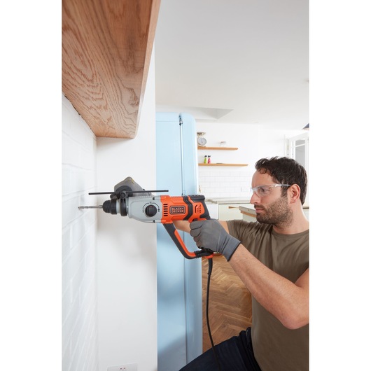 Photo of BLACKDECKER BEHS02K rotary hammer drill used on white brick wall in a modern kitchen.
