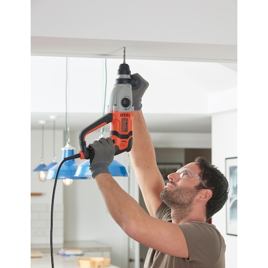 Photo of BLACKDECKER BEHS02K corded hammer drill held by person drilling into ceiling indoors.