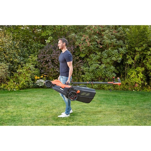 BLACKDECKER BEMW481BH lawn mower with handle being carried by person outdoors on grass.