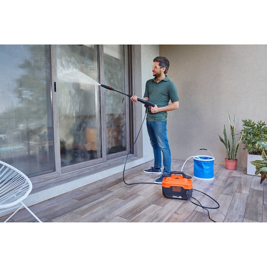 BLACKDECKER BEPW1300H portable pressure washer cleaning glass door on patio.