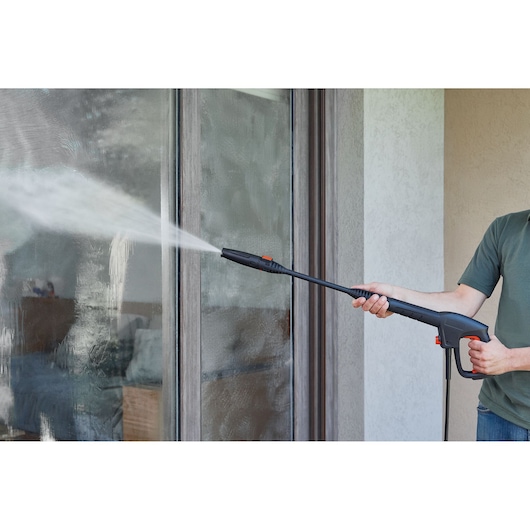 BLACKDECKER BEPW1300H pressure washer cleaning glass door, indoor angle, spray nozzle in use