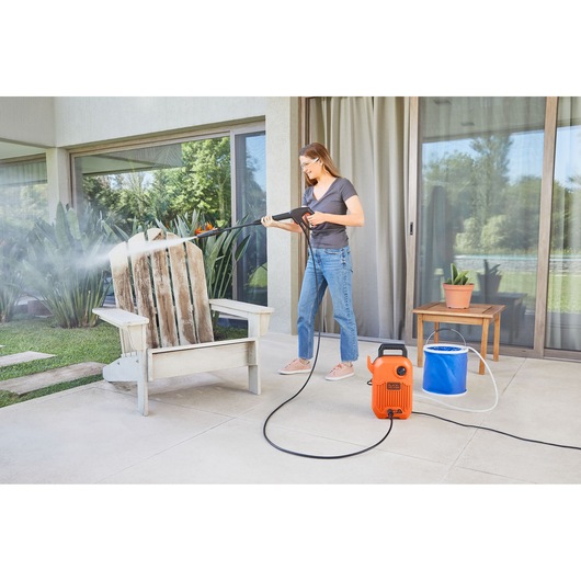 BLACKDECKER BEPW1300 pressure washer used outdoors to clean a wooden chair on patio.
