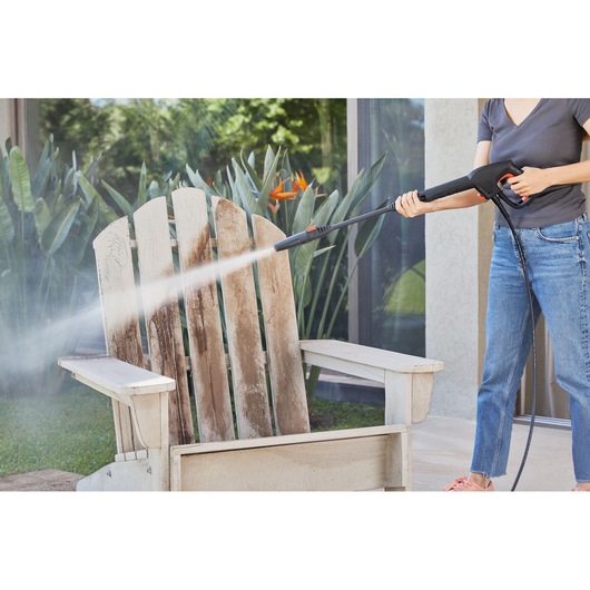 BLACKDECKER BEPW1300 pressure washer cleaning a weathered wooden outdoor chair