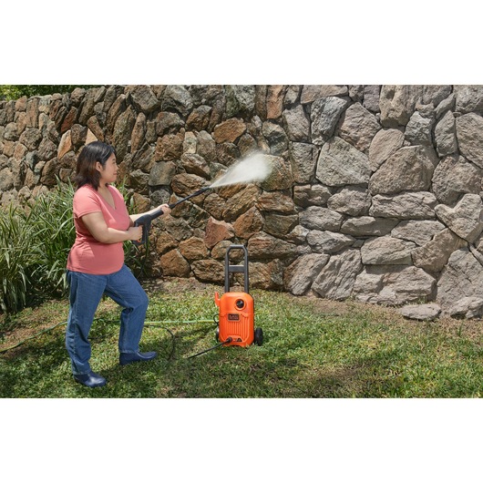 BLACKDECKER BEPW1650 pressure washer cleaning a stone wall outdoors.