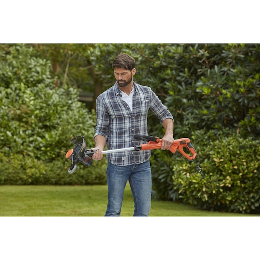 BLACKDECKER BESTE628 grass trimmer with orange handle and silver shaft held outdoors.