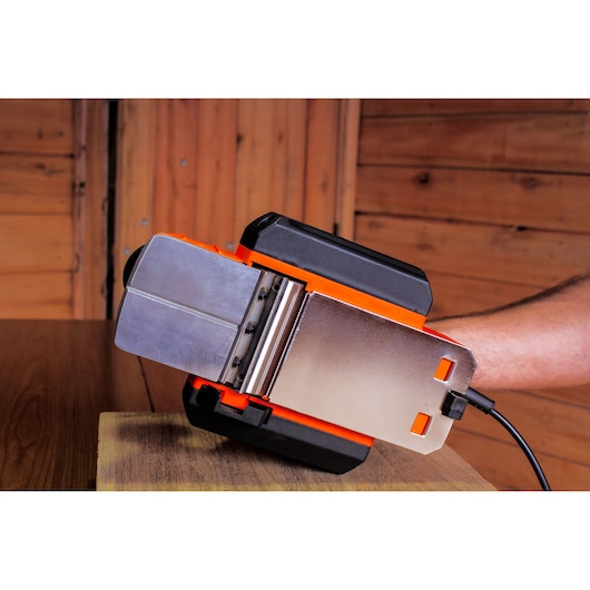 BLACKDECKER BEW712 electric belt sander close-up, black and orange, on wood surface, side angle.