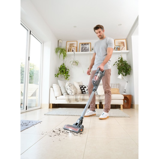 BLACKDECKER BHFEA18D1 stick vacuum cleaner cleaning tiled floor in bright living room.