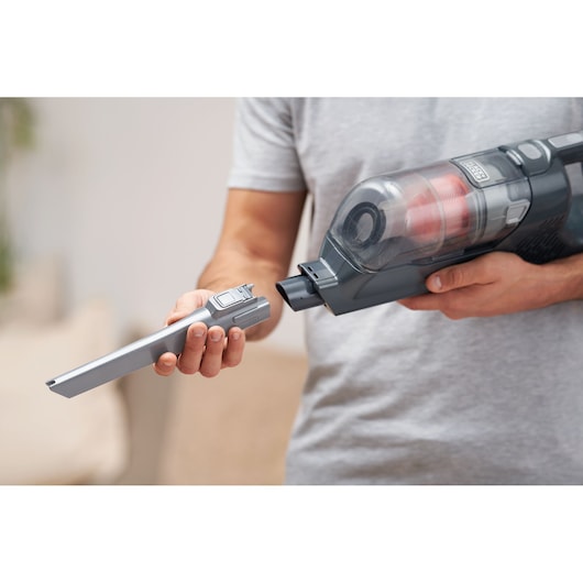 BLACKDECKER BHFEA18D1 cordless vacuum held by a person attaching a slim nozzle accessory, close-up indoor scene.