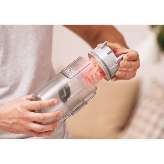 Photo of BLACKDECKER BHFEA18D1 vacuum dust canister being opened, showing orange filter and gray lid.