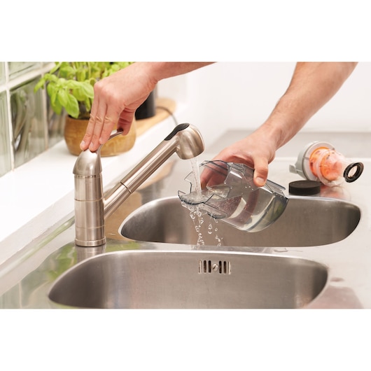 BLACKDECKER BHFEA18D1 vacuum dust container rinsed under faucet in kitchen sink, photography close-up.