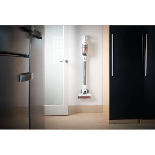 Photo of BLACKDECKER BHFEA515J cordless stick vacuum cleaner mounted on a white kitchen wall.