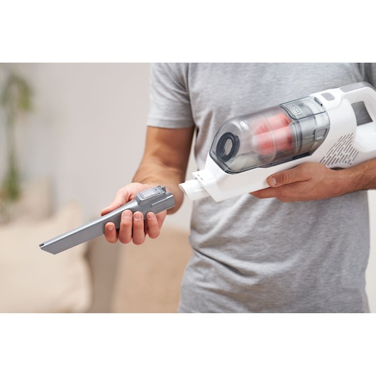 Person attaching a long nozzle to BLACK+DECKER BHFEA515J cordless handheld vacuum cleaner indoors.