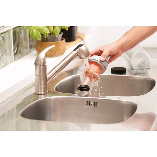 BLACKDECKER BHFEA515J vacuum filter being cleaned under a kitchen faucet, close-up view.