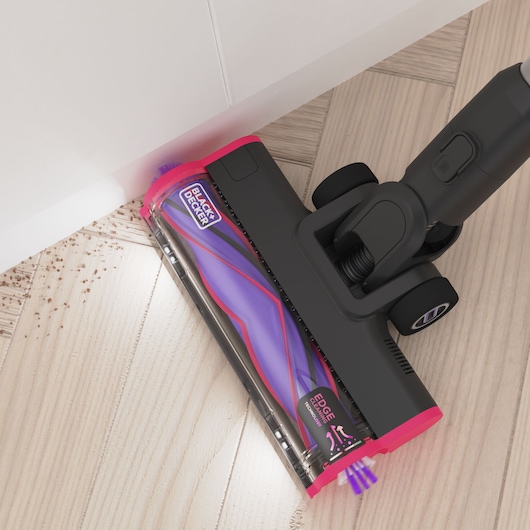 BLACK+DECKER BHFEA640WG vacuum cleaner head in black and pink cleaning debris from a light wood floor, close-up.