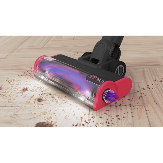 BLACKDECKER BHFEA640WP vacuum cleaner head in pink and black cleaning debris on wood floor, front angle.