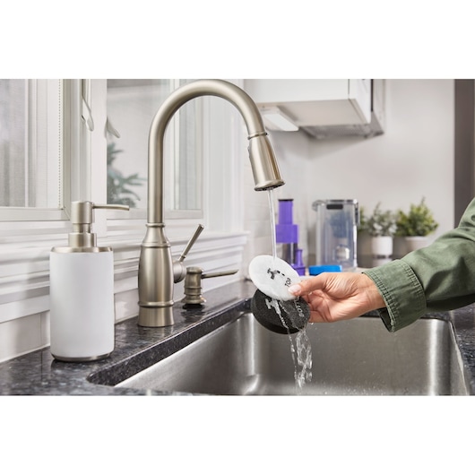 BLACKDECKER BHFEA640WP cleaning pads being rinsed under kitchen faucet in photography product category.